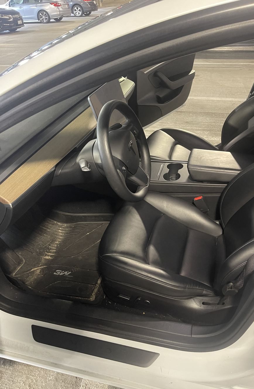 Tesla Model 3 driver floor before detailing, muddy mats